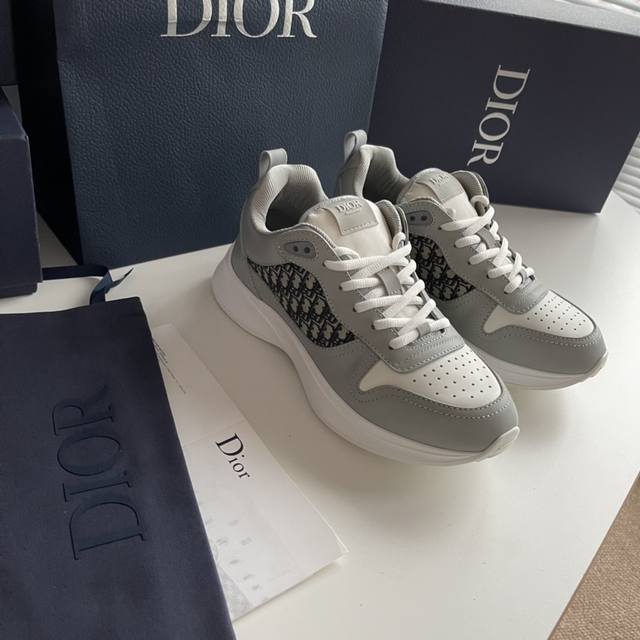 新款b25 Runner 运动鞋 结合运动版型与 Dior 优雅的经典标识。采用灰色绒面革和白色网眼织物精心制作，饰以蓝色和白色 Oblique 印花和透明橡胶