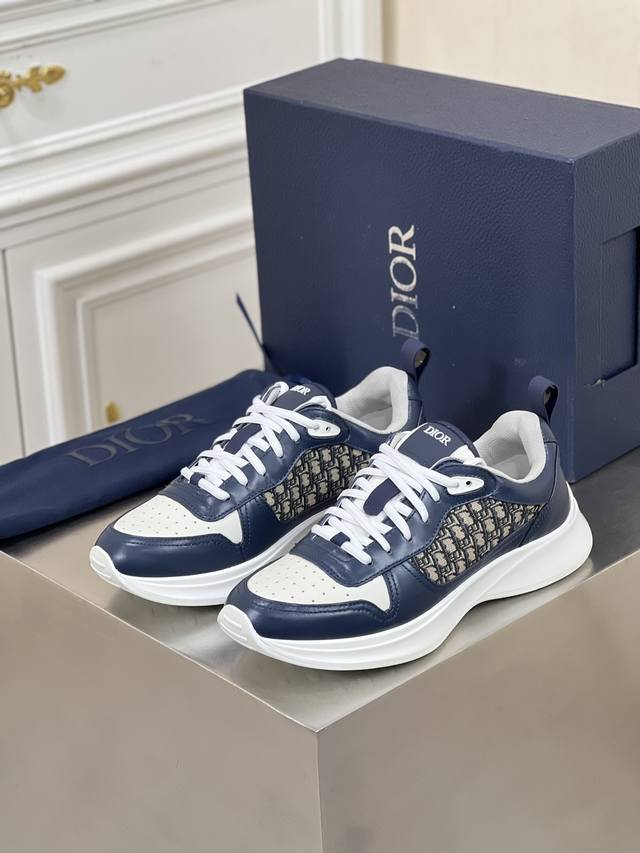 新品dio*低帮 B25 Runner 运动鞋 本款结合运动版型与 Dior 优雅的经典标识。采用灰色绒面革和白色网眼织物精心制作，饰以蓝色和白色 Obliqu